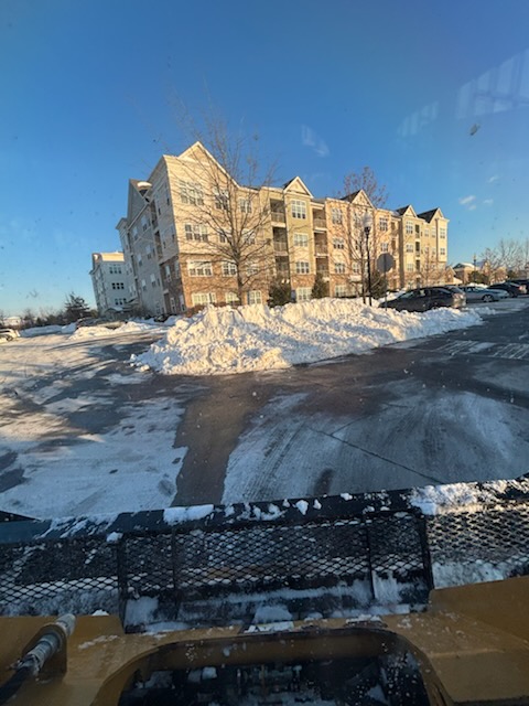 A cleared commercial parking lot from the plow truck, snow pushed into long banks in front of an apartment building